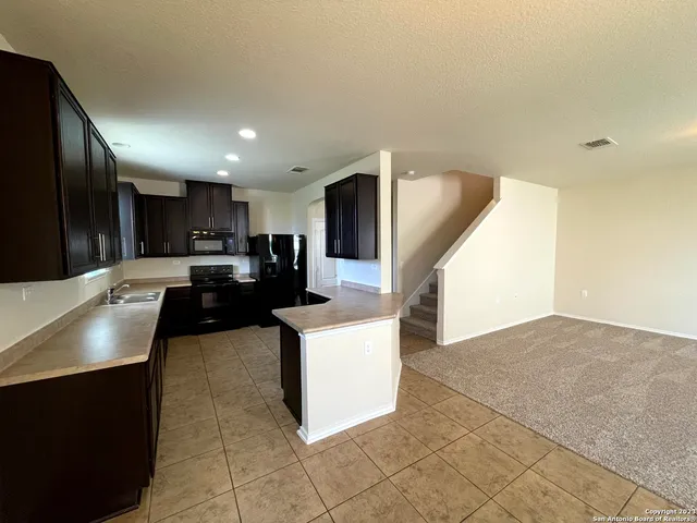 a kitchen with stainless steel appliances kitchen island granite countertop a refrigerator a stove a sink and a oven