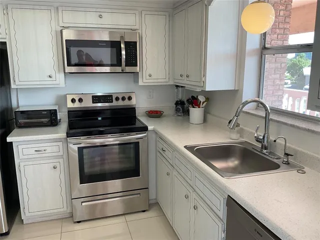 a kitchen with stainless steel appliances white cabinets white stove a refrigerator and a microwave