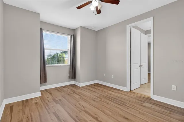 a view of an empty room with wooden floor and a window