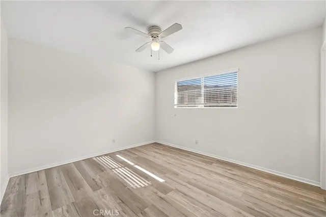 an empty room with wooden floor chandelier fan and windows