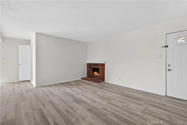 a view of an empty room with wooden floor and a fireplace