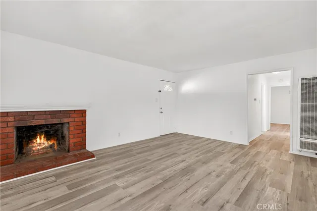 a view of an empty room with wooden floor fire place and a fireplace