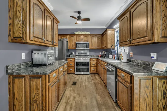 a kitchen with stainless steel appliances granite countertop wooden cabinets a stove top oven a sink and dishwasher