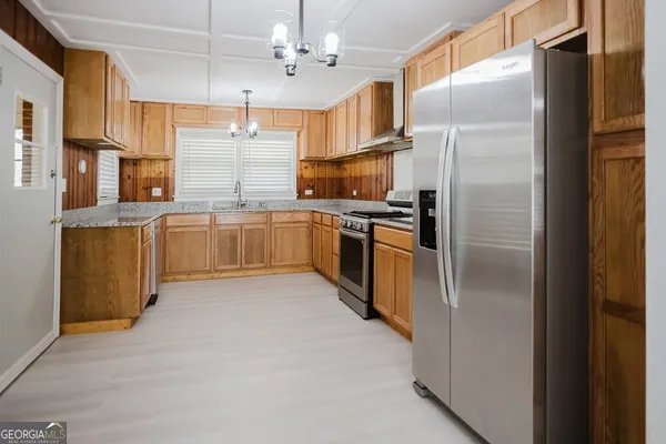 a kitchen with stainless steel appliances granite countertop a refrigerator a stove and a sink