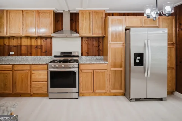a kitchen with granite countertop a stainless steel stove a refrigerator and cabinets
