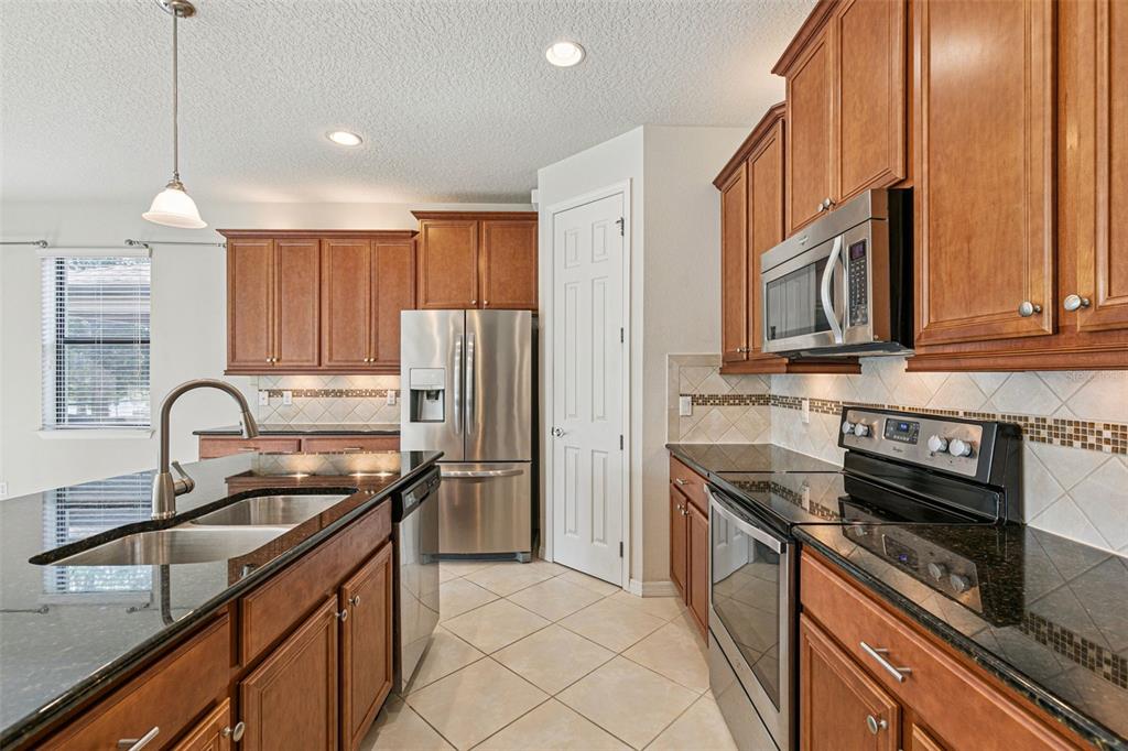 7137 Beek Street Windermere, FL 34786 - Photo 5 of 33 a kitchen with kitchen island granite countertop a sink stainless steel appliances and cabinets