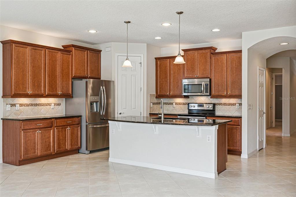 7137 Beek Street Windermere, FL 34786 - Photo 7 of 33 a kitchen with stainless steel appliances granite countertop a refrigerator a stove top oven a sink and dishwasher
