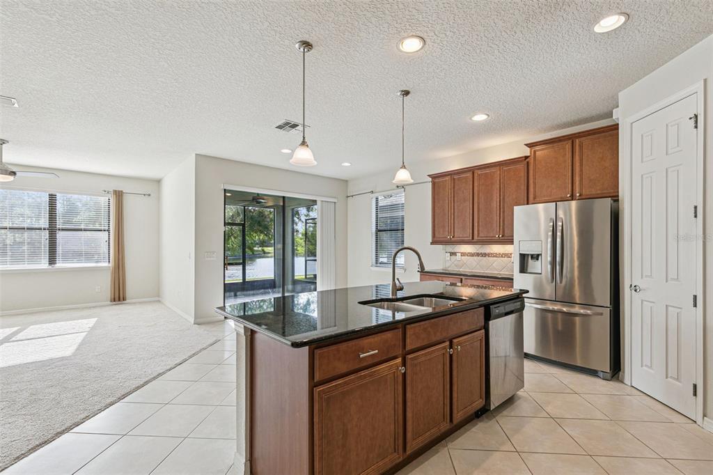 7137 Beek Street Windermere, FL 34786 - Photo 9 of 33 a kitchen with stainless steel appliances granite countertop a stove a refrigerator and a sink with wooden cabinets