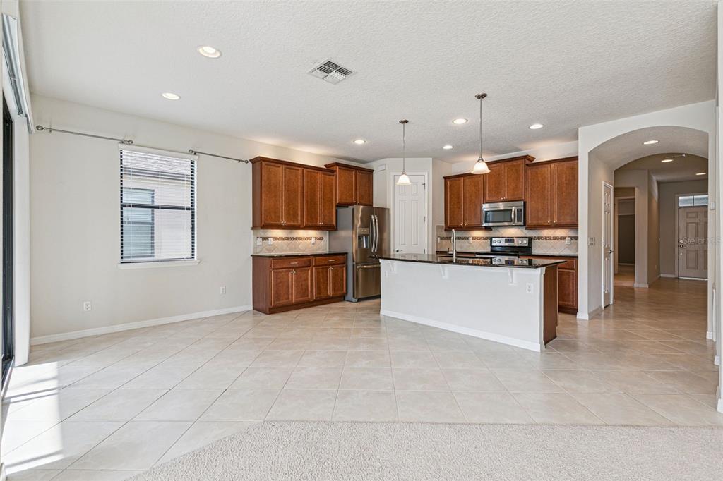 7137 Beek Street Windermere, FL 34786 - Photo 10 of 33 a large kitchen with kitchen island a stove a sink dishwasher a refrigerator and white cabinets with wooden floor