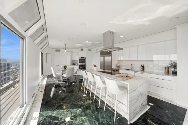 a view of a kitchen with kitchen island a stove a refrigerator a sink dishwasher with a dining table and chairs with wooden floor