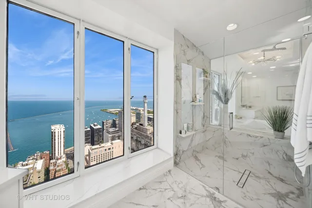 a view of a hallway with wooden floor and a glass door shower