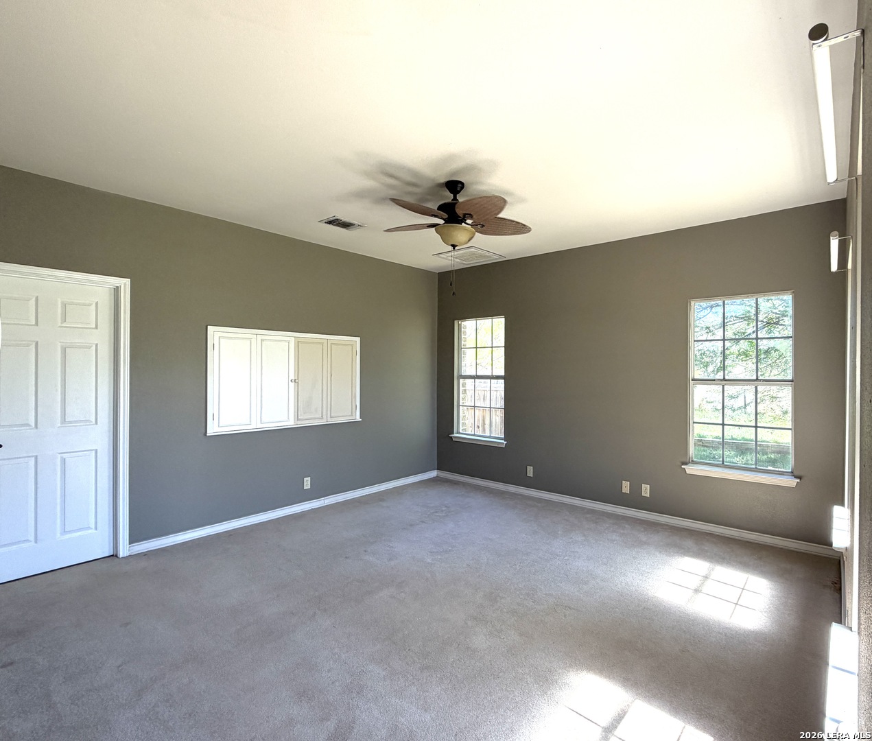 10565 Briggs Road Atascosa, TX 78002 - Photo 21 of 59 an empty room with windows and chandelier fan