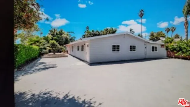 a view of a white house with a yard and potted plants