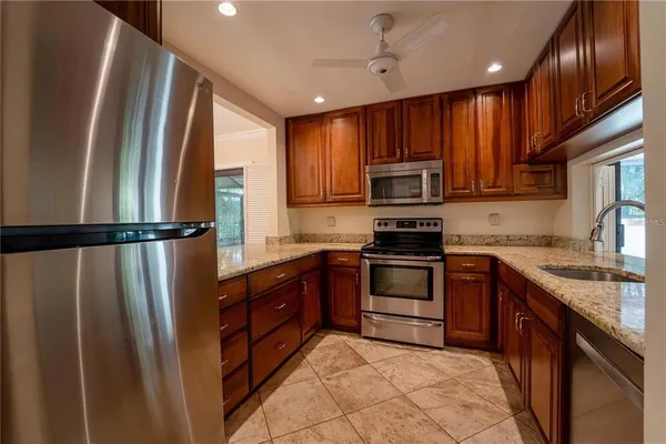 a kitchen with stainless steel appliances granite countertop a refrigerator a sink a stove a microwave and wooden cabinets