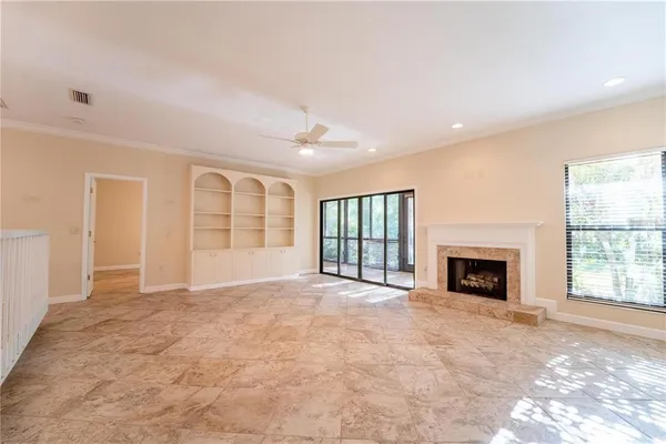 an empty room with windows and fireplace