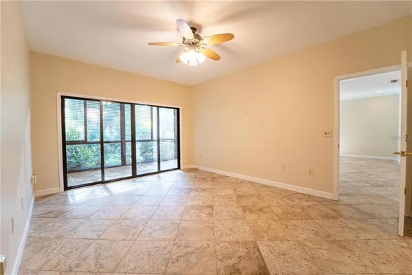 an empty room with chandelier fan and windows