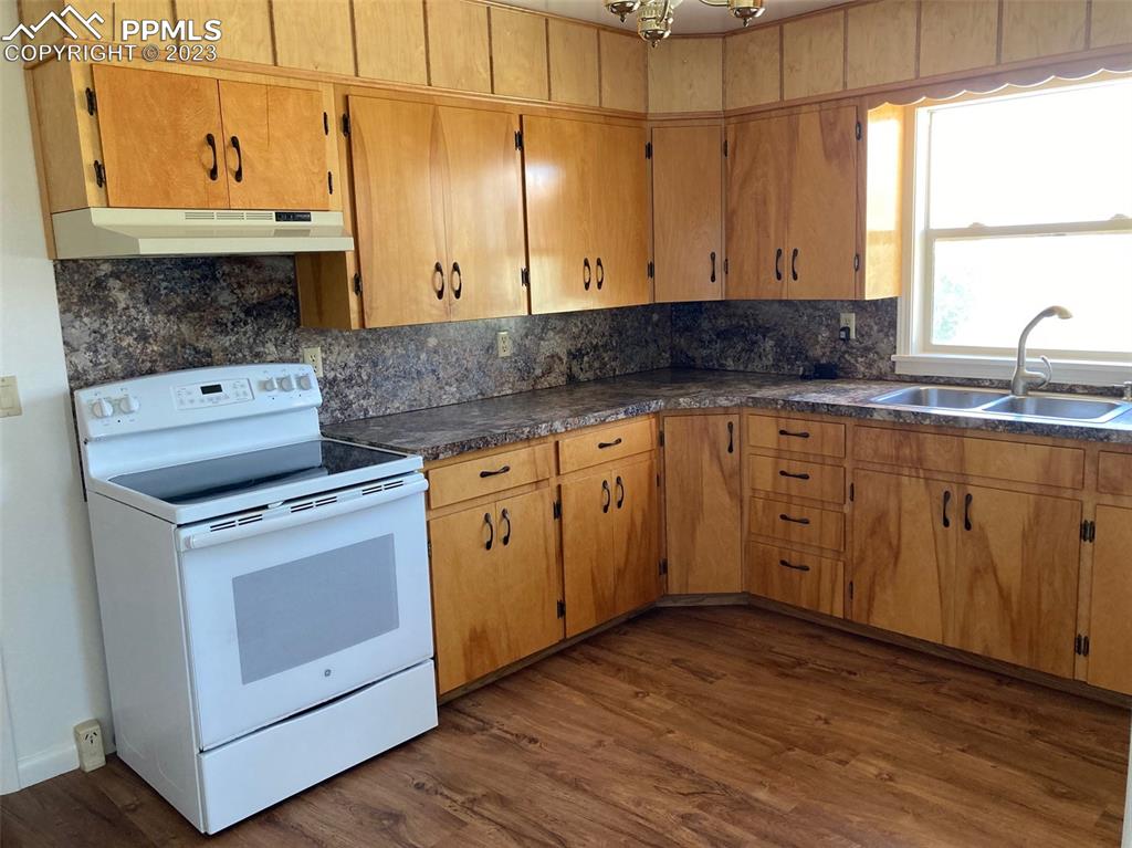 355 North Rush Road Rush, CO 80833 - Photo 25 of 41 a kitchen with stainless steel appliances a stove a sink and white cabinets with wooden floor