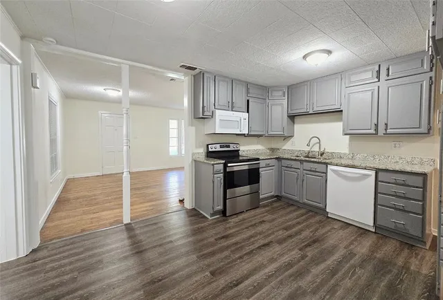 a kitchen with granite countertop a sink cabinets and stainless steel appliances