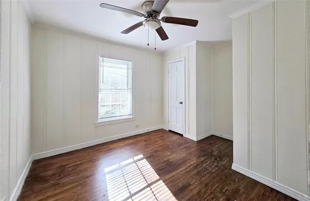 a view of empty room with wooden floor and fan