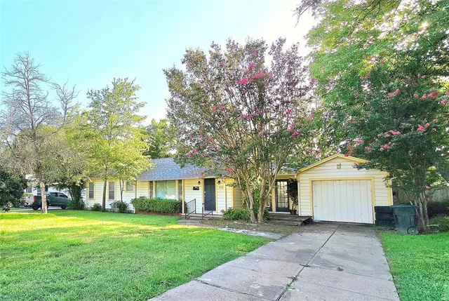 a front view of a house with a garden and trees