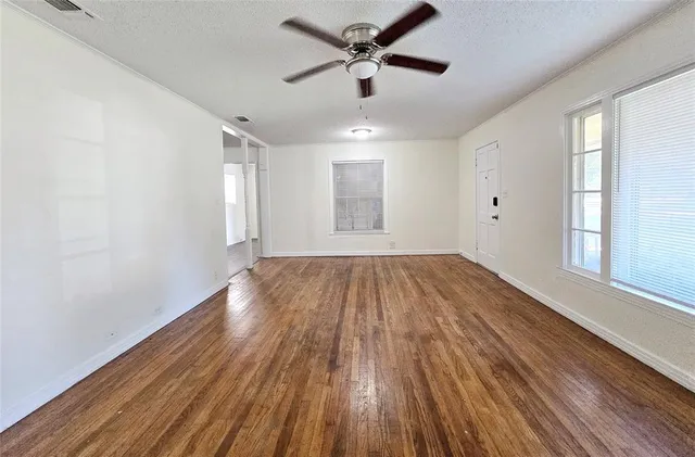 a view of empty room with wooden floor and fan