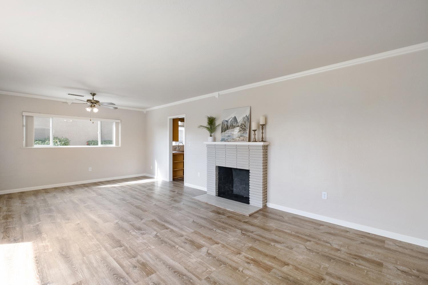 1223 Cyrier Avenue Reedley, CA 93654 - Photo 4 of 21 a view of an empty room with wooden floor fireplace and a window