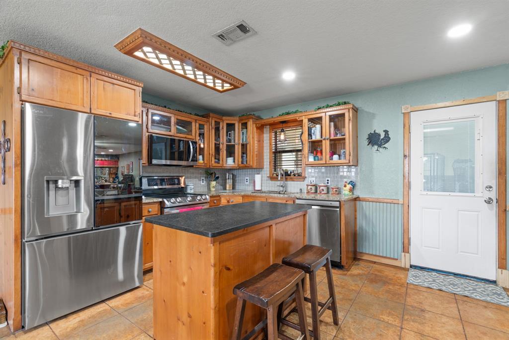5058 West Highway 199 Springtown, TX 76082 - Photo 16 of 40 a kitchen with stainless steel appliances granite countertop a refrigerator and a stove top oven