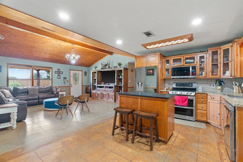 5058 West Highway 199 Springtown, TX 76082 - Photo 17 of 40 a living room with stainless steel appliances kitchen island granite countertop furniture and a wooden floor