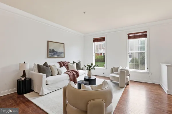 a living room with couches a kitchen island with cabinets and wooden floor