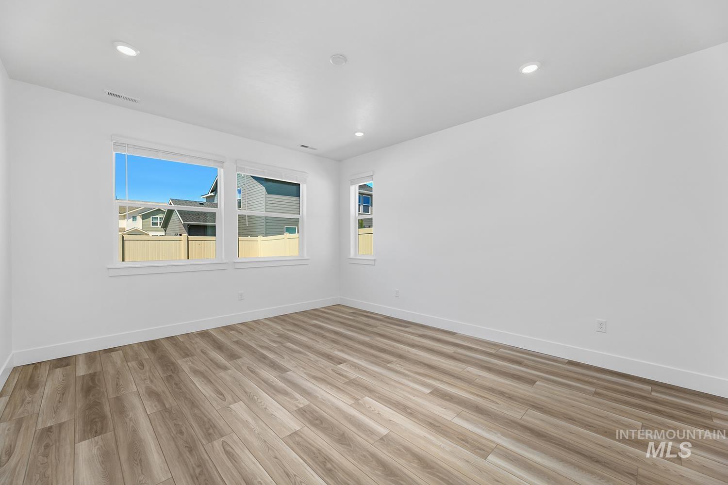 4548 West Wapoot Street Meridian, ID 83646 - Photo 13 of 17 Room featuring wood-finish flooring, recessed lighting, and multiple windows with blinds