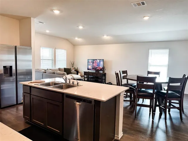 a kitchen with stainless steel appliances granite countertop a sink a stove a dining table and chairs