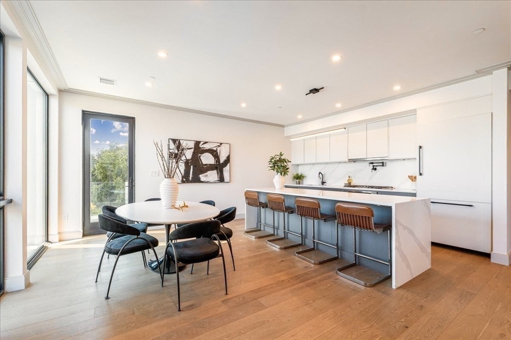 57 University Road, Unit 3 Brookline, MA 02445 - Photo 5 of 20 a kitchen with stainless steel appliances kitchen island granite countertop a table chairs sink and cabinets