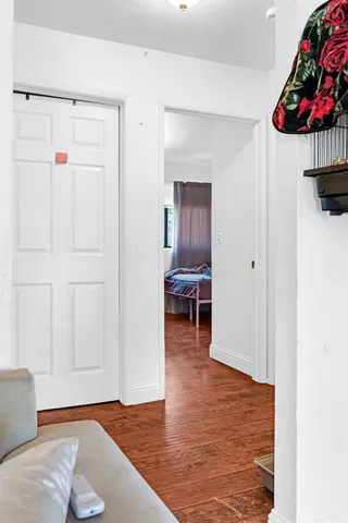 a view of an empty room with wooden floor and a window