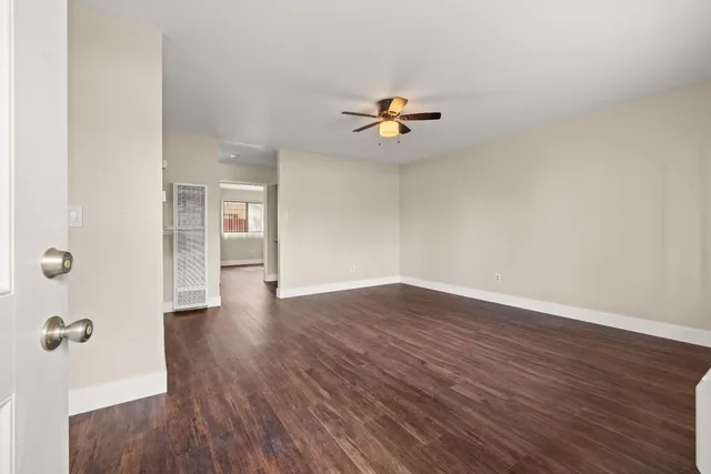 an empty room with wooden floor a ceiling fan and windows