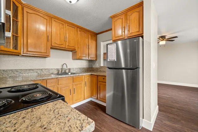 a kitchen with stainless steel appliances granite countertop wooden cabinets a sink and dishwasher a stove with wooden floor