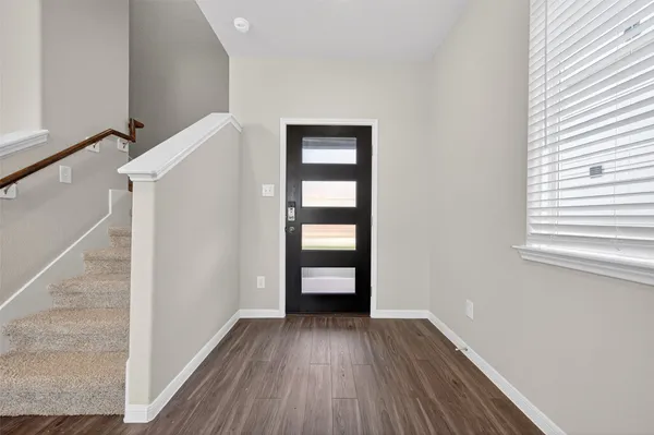 a view of an empty room with wooden floor and a ceiling fan