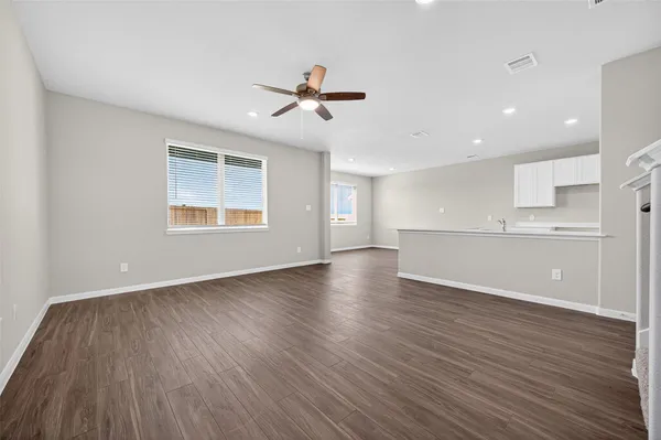 a view of empty room with wooden floor and fan