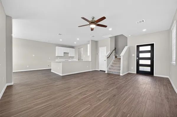 a kitchen with stainless steel appliances granite countertop a sink a stove a refrigerator and white cabinets with wooden floor