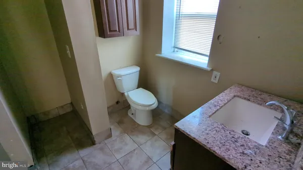 a bathroom with a granite countertop sink and a toilet