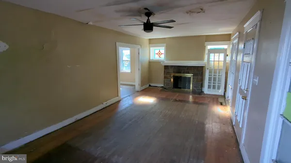 an empty room with wooden floor a fireplace and windows