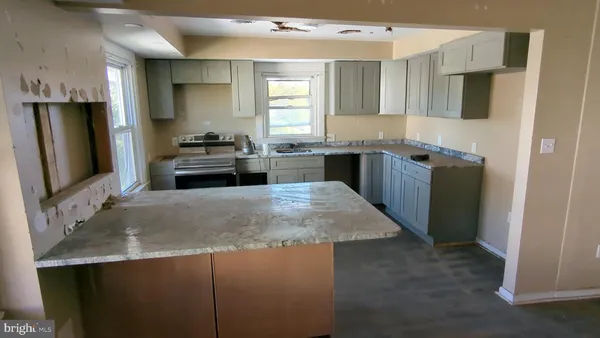 a kitchen with kitchen island granite countertop a sink stove and refrigerator