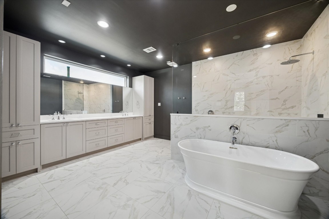 4219 Alba Road Houston, TX 77018 - Photo 23 of 39 Spa-inspired primary bath with freestanding soaking tub, oversized walk-in shower, marble-look tile, and dramatic dark accent walls.