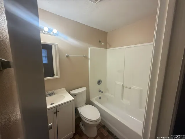 a bathroom with a granite countertop toilet a sink and a mirror