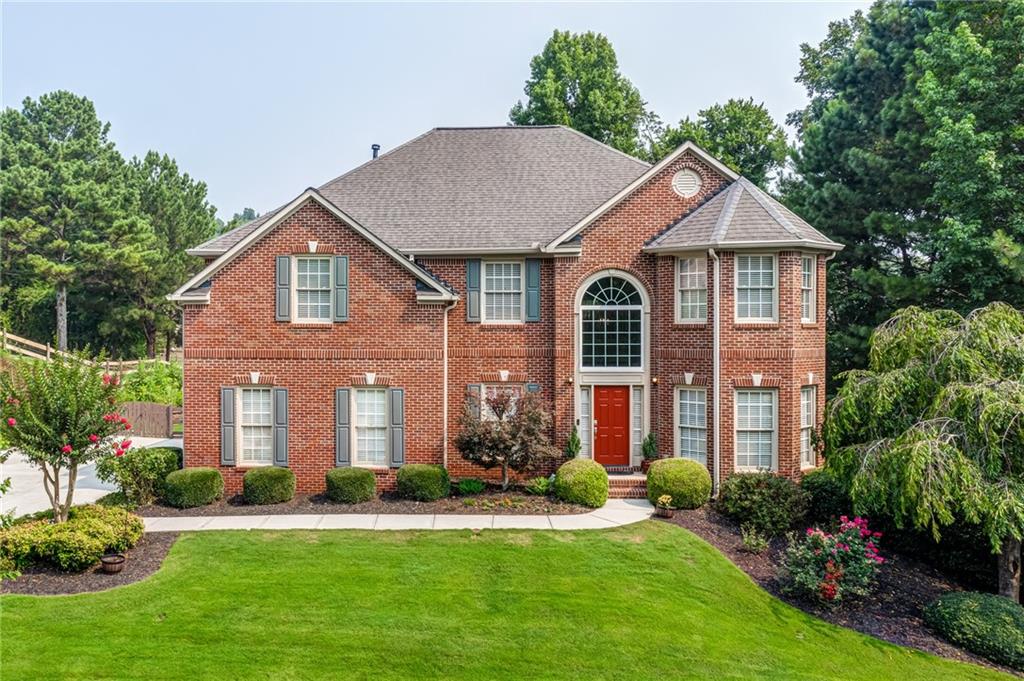 a front view of a house with a yard and potted plants
