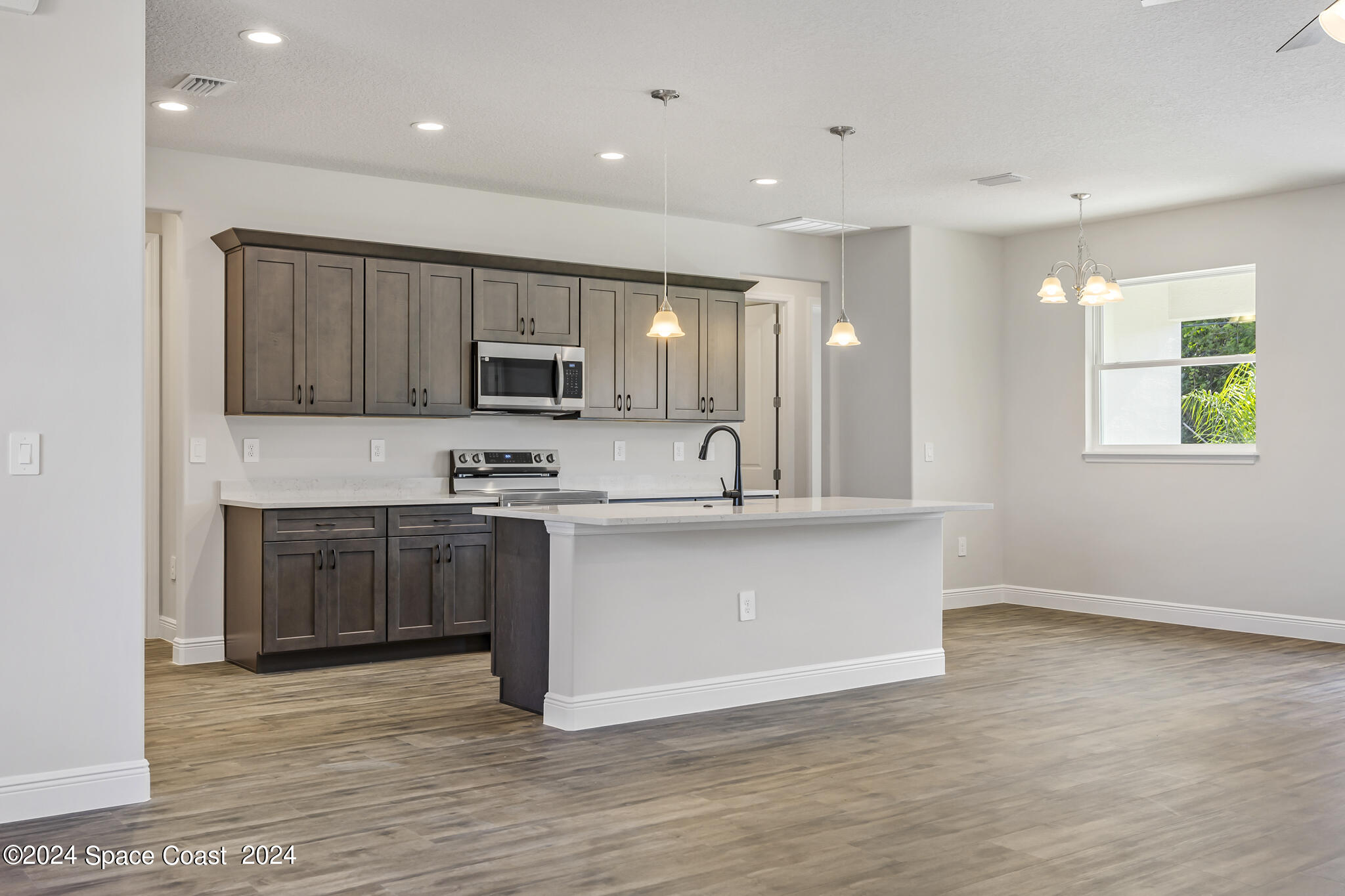 1368 Rabbit Street Southeast Palm Bay, FL 32909 - Photo 27 of 31 a large kitchen with stainless steel appliances granite countertop a stove a sink and a microwave