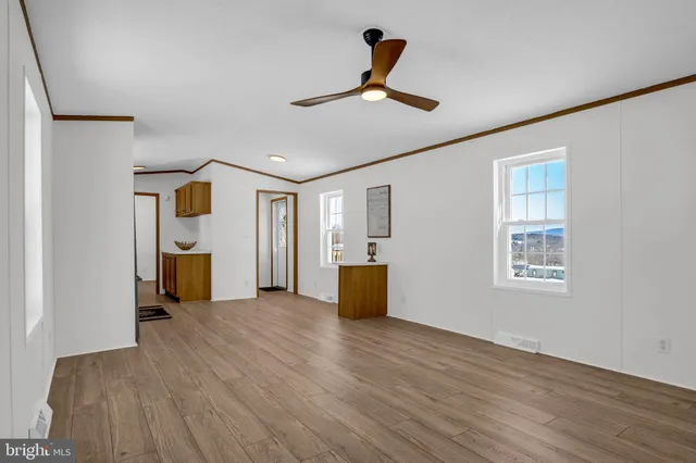 a view of a livingroom with wooden floor and a ceiling fan