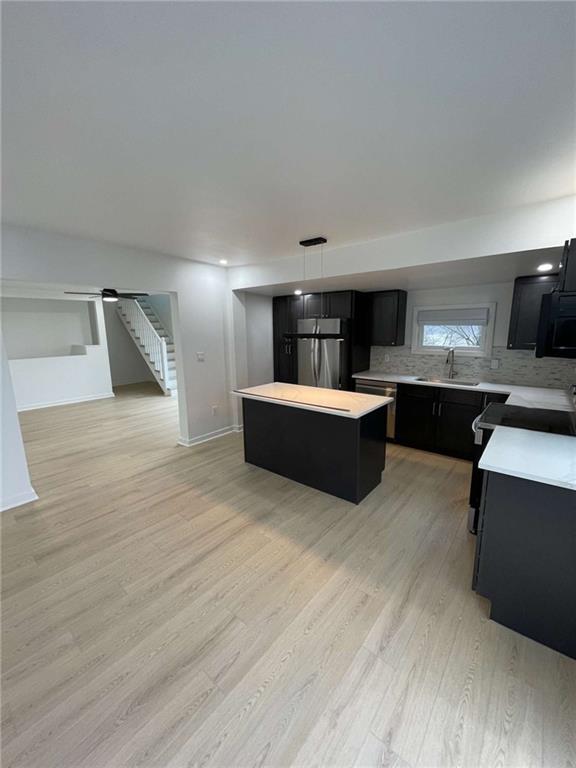 107 Shoup Street, Unit 2 Pittsburgh, PA 15209 - Photo 29 of 40 a large room with kitchen island stainless steel appliances wooden floor and window