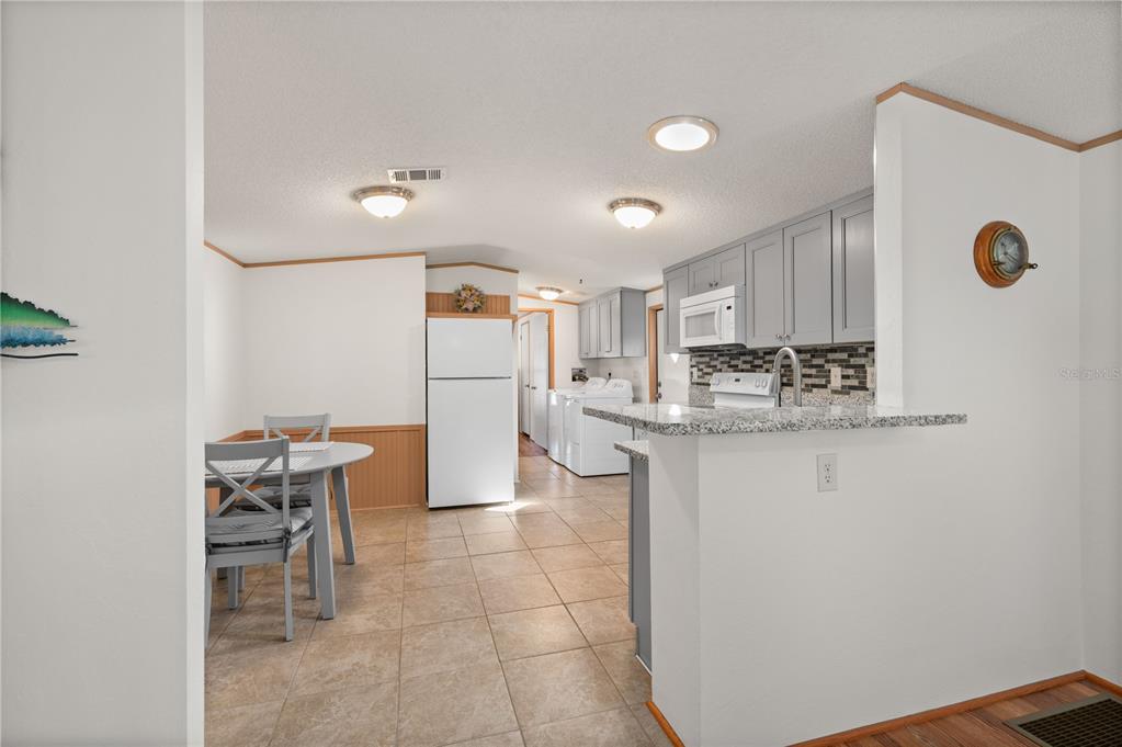 24437 Harbor View Road, Unit 114 Punta Gorda, FL 33980 - Photo 16 of 56 a kitchen with kitchen island cabinets and chairs in it