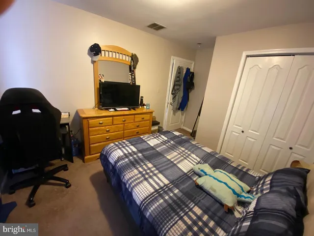 a bedroom with a bed and a dresser with rug