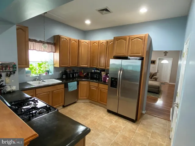 a kitchen with stainless steel appliances kitchen island granite countertop a refrigerator and a sink